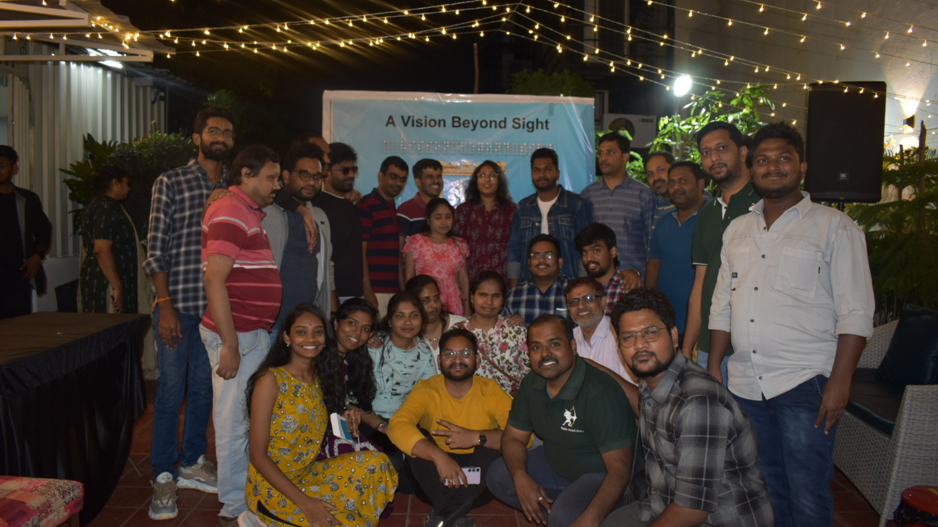 Group of volunteers and participants posing together in front of a banner reading ‘A Vision Beyond Sight’ during the Ability Awareness event.